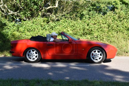 Téléchargez les photos : Powderham, Devon, uk. 9 juillet 2022. Voiture classique Porsche 944 Cabriolet en Guards rouge. Photo de conduite sur une route de campagne un jour d'été. - en image libre de droit