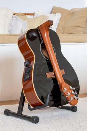 Photo for Banwell, North Somerset, UK. March 8th 2022. Voyage Air foldable guitar. Unique hinged acoustic guitar in black. Electro acoustic guitar on a stand whilst in folded configuration. Backpack guitar. - Royalty Free Image