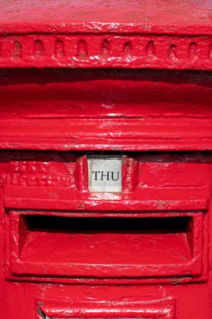 Donnerstag Wort als THU auf einem britischen roten Briefkasten gezeigt. Optisch auffälliges und farbenfrohes Hochformatbild, das den Wochentag darstellt. Knallrot. Briefkasten und Postbild. 