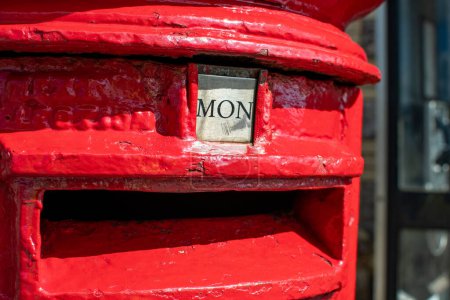 Monday word shown as MON on a British red letter box. Visually striking and colorful portrait format image depicting the day of the week. Bright red. Letter box and postal image. 