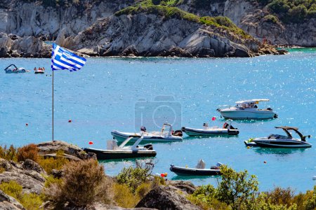 Photo for Yachts in Gulf of Sithonia and th Greek flag on flagpole. coastline in foreground and background - Royalty Free Image
