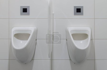 Photo for Two white urinals with Ideal Standard Eurovit model numbers V553801 and K5539 are mounted on a wall. The urinals have a suction flush and are new. - Royalty Free Image