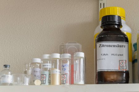 Un estante lleno de varias botellas químicas con etiquetas. Las etiquetas contienen información sobre los productos químicos, incluidos los símbolos de peligro.