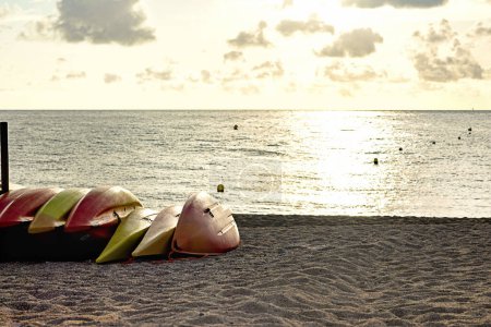los kayaks colocados en la arena de la playa, vistas al mar y al amanecer o al atardecer