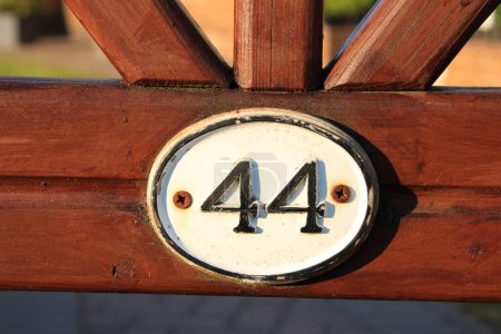 Photo for Up close picture of wooden gate with number 44 white house sign with Black numbering - Royalty Free Image
