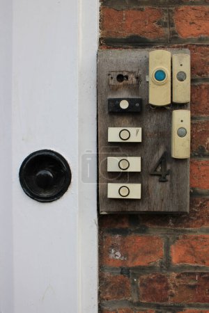 Téléchargez les photos : Façade de la maison avec 7 sonnettes analogiques modernes attachées à un vieux morceau de bois usé avec la maison numéro 4 attachée - en image libre de droit