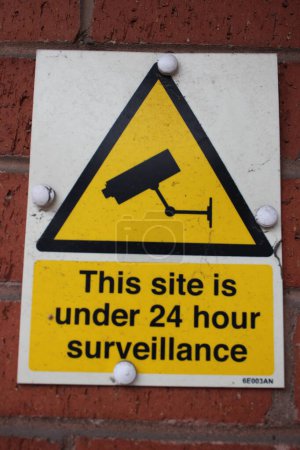 Téléchargez les photos : Panneau jaune et blanc "Ce site est sous surveillance 24 heures" - en image libre de droit