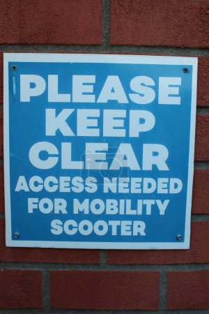 Photo for White and blue sign " Please Keep Clear access needed for mobility scooter" UK - Royalty Free Image