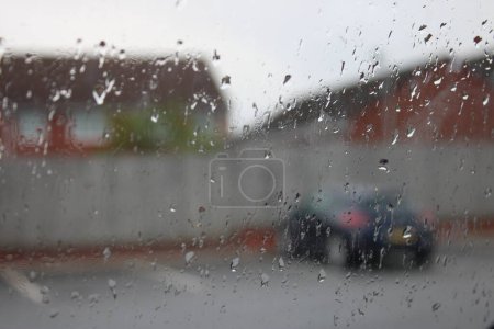 Foto de Cierre de la lluvia en una ventana de coche con aparcamiento borroso y casas en el fondo - Imagen libre de derechos