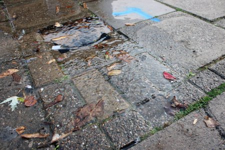 Photo for Broken water main in village street leaking water onto pavement - Royalty Free Image