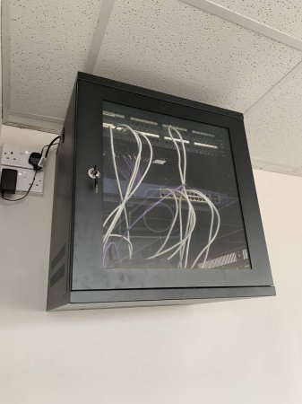 Foto de Armario de TI montado en la pared negro con un interruptor de red y panel de conexión dentro - Imagen libre de derechos