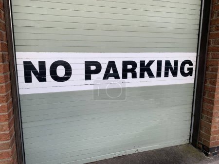 Photo for No Parking sign attached to a grey metal garage door taken on a rural street UK - Royalty Free Image