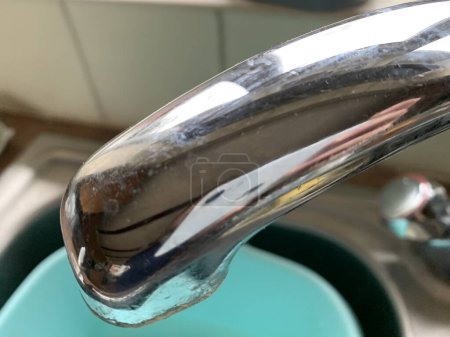 Close up of silver tap in a domestic kitchen, Perspective focus, Sink and bowl in background blurred