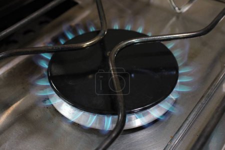 Gros plan de la plaque de cuisson au gaz allumée à haute température, flamme bleue visible
