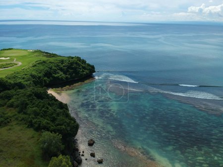 Foto de Vista aérea desde la playa de Balangan con acantilados de isla verde, cielos despejados y mar azul oscuro - Imagen libre de derechos