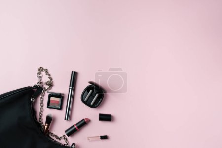 Women's things fall out of a bag on a pink background