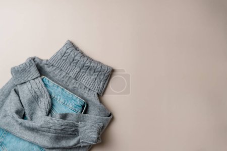 Winter women's clothing on a beige background. Flat lay, top view.