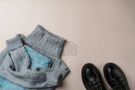 Winter women's clothing on a beige background. Flat lay, top view.