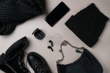 Total black accessories on beige background. Flat lay, top view.