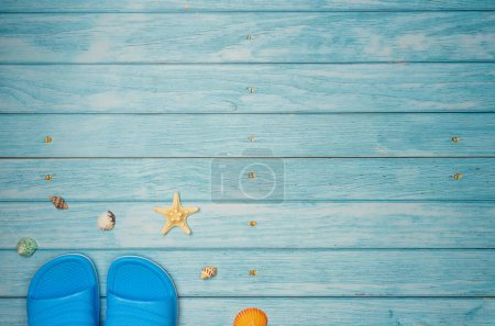Flipflops mit Muscheln auf blauem Holzhintergrund mit Kopierraum