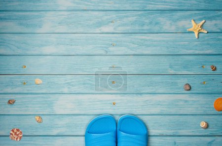 Tongs avec coquilles sur fond en bois bleu avec espace de copie