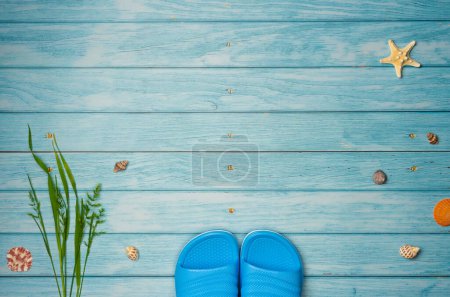 Flipflops mit Muscheln auf blauem Holzhintergrund mit Kopierraum