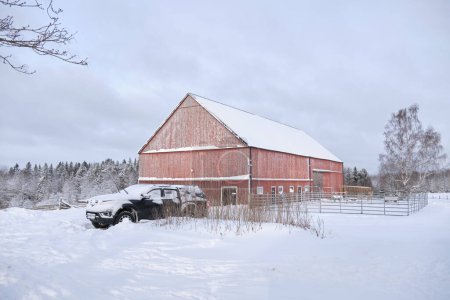 Typisch schwedisch rot gestrichenes landwirtschaftliches Gebäude in Bredebolet in Skaraborg in Vaestra Goetaland in Schweden im Winter