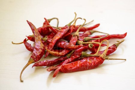 A bunch of dried red chilies on a wooden background. Chili pepper serves as one of the world-class spices in delicious recipes. It is locally known as Shukna Morich in Bangladesh.
