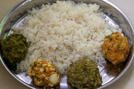 Comida tradicional bengalí (bangladesí) en una placa de acero. Arroz blanco con cuatro tipos de vorta como Aloo Bharta, Egg Bharta, Chepa Shutki Bharta y Shim Bharta.