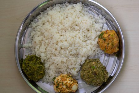 Traditionelle bengalische (bangladeschische) Speisen auf einer Stahlplatte. Weißer Reis mit vier Arten von Vorta wie Aloo Bharta, Egg Bharta, Chepa Shutki Bharta und Shim Bharta. Ansicht von oben.
