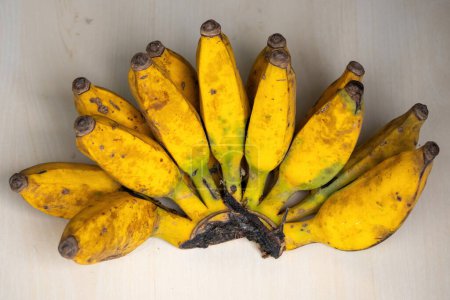 Ein Bündel gelber reifer Bananen auf einem hölzernen Hintergrund. Bananen sind eine nahrhafte Frucht mit vielen gesundheitlichen Vorteilen.