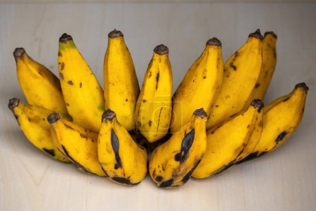 Ein Bündel reifer gelber Bananen auf einem hölzernen Hintergrund. Bananen sind reich an Kalium und anderen wichtigen Mineralien und Vitaminen, die Ihrem Körper helfen, wichtige Funktionen zu erfüllen.