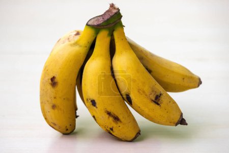 Un ramo de plátanos amarillos sobre un fondo blanquecino. Los plátanos son frutas saludables, pueden ser una buena fuente de nutrientes.