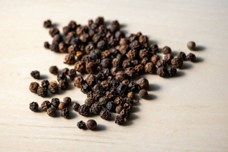 Black pepper isolated on a wooden background. Black pepper is a low-calorie spice that adds flavor to food without adding extra calories. It has many health benefits.