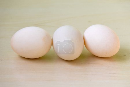Tres huevos de pato blanco aislados sobre un fondo de madera. Los huevos de pato son una buena fuente de nutrición, contienen más proteínas, vitaminas, minerales y grasas saludables que los huevos de pollo..