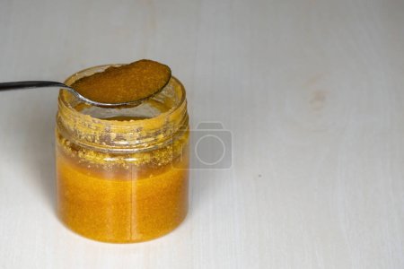 Ghee o mantequilla clarificada en un frasco con cuchara de acero sobre fondo de madera. El Ghee es una rica fuente de vitaminas, antioxidantes y grasas saludables.. 