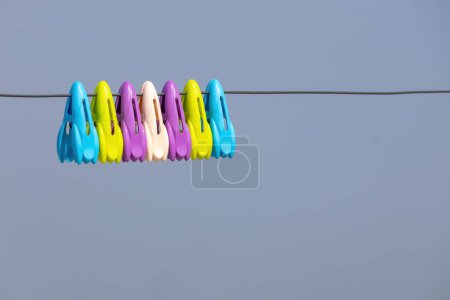 Foto de Pinzas de ropa de diferentes colores en el tendedero con fondo de cielo azul claro. - Imagen libre de derechos