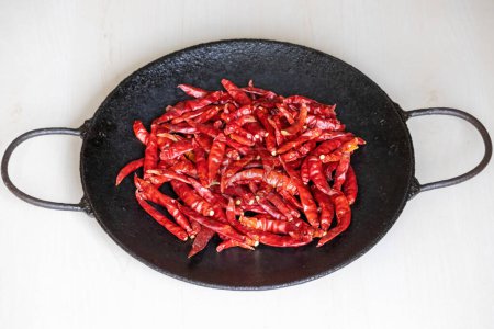 Dry red chilies are taken for frying in a pan.
