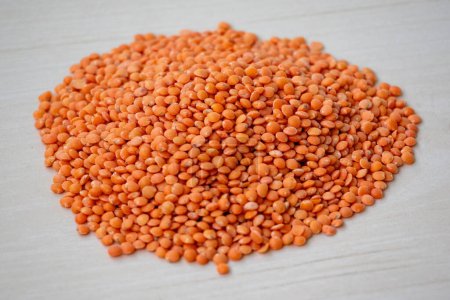 Raw red lentils isolated on a wooden background. Incorporating red lentils into your diet can help you easily meet fiber and protein needs.