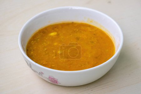 Lenteja roja o masoor dal bhuna o ghono dal en un tazón blanco sobre fondo de madera. Es comida tradicional de Bangladesh y la región de Bengala de la India.. 