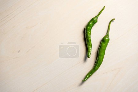 Frische grüne Chilischoten auf einem hölzernen Hintergrund. In Bangladesch heißt sie Kacha Morich.
