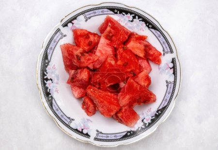 Frische Wassermelonenscheibe auf einem Teller auf weißem Hintergrund. In Bangladesch wird sie Tormuj genannt. Ansicht von oben