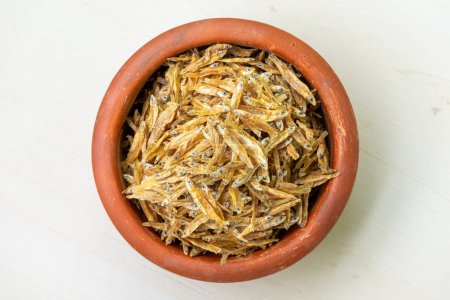 Photo for A pile of dried fish (Corica soborna) in an earthen pot. Locally In Bangladesh, It is called Kachki Shutki. It is also known as Ganges river sprat, Kachki, Kechki, Gura mach. Top view - Royalty Free Image