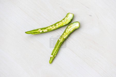 Green chili peppers cut in half on a wooden background