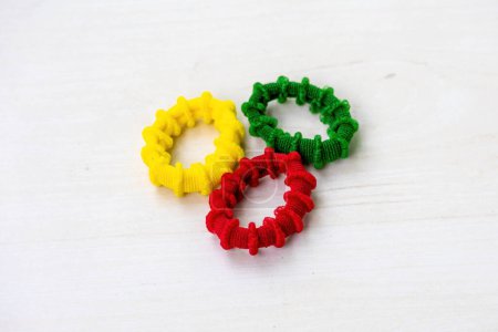 Colorful rubber bands isolated on wooden background. It is circular bands of fabric-covered elastic used to fasten women's hair.