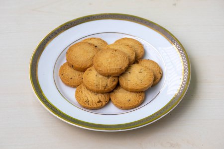 Pile de délicieux biscuits servis sur une assiette blanche sur un fond en bois. Les biscuits peuvent être consommés à tout moment, y compris le petit déjeuner, le déjeuner, le dîner et le dessert.