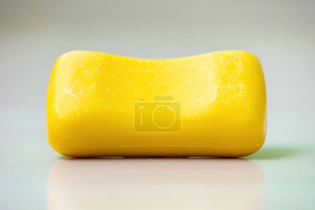 Una barra de jabón amarillo sobre un fondo blanco