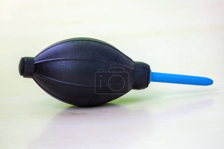 Rubber air blower pump dust cleaner isolated on wooden background. This tool can clean dust from cameras, camera lenses, filters, musical instruments, computers, keyboards, cellphones, etc.