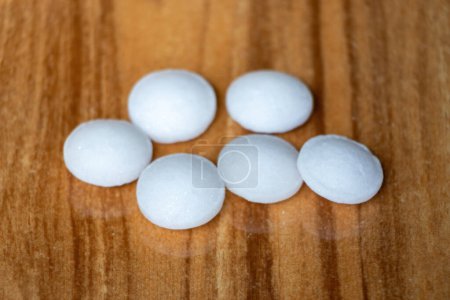 Naphthalene mothballs isolated on wooden background. It is also known as moth flakes, naphthalin, antimite, and hexalene.