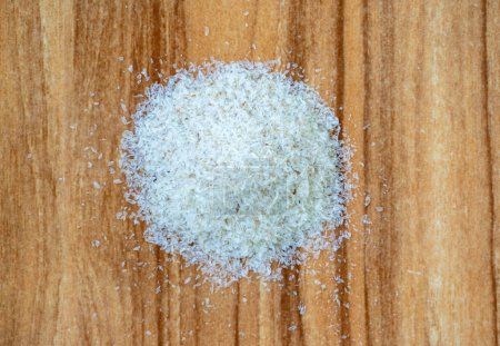 Psyllium husk isolated on wooden background. It is a dietary fiber that comes from the seeds of the Plantago Ovata plant. It's a common home remedy for constipation and other health issues.